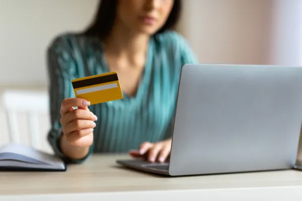 Donna con carta di pagamento davanti a un computer portatile.
