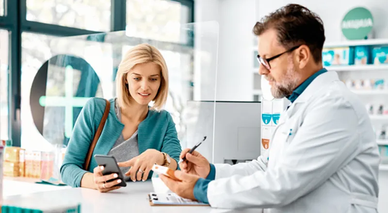 Farmacista e cliente consultano informazioni tramite uno smartphone.